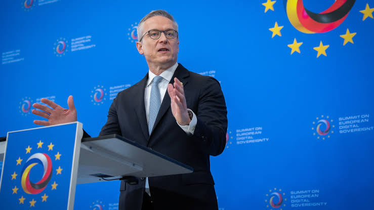 Karsten Wildberger speaking at a lectern in front of a blue backdrop with the logo of the Summit on European Digital Sovereignty and European stars