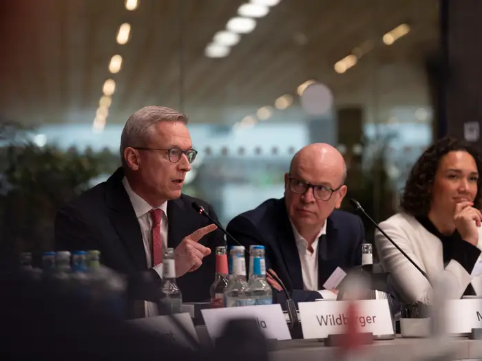 Karsten Wildberger speaking at a panel table behind a name card reading Wildberger