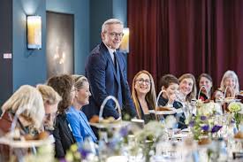 Karsten Wildberger standing and speaking to guests seated at a dinner table