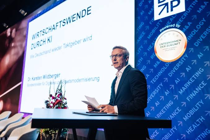Karsten Wildberger on stage in front of a screen titled Wirtschaftswende durch KI
