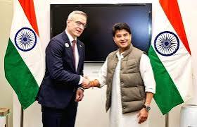 Karsten Wildberger shaking hands with an Indian official between Indian flags
