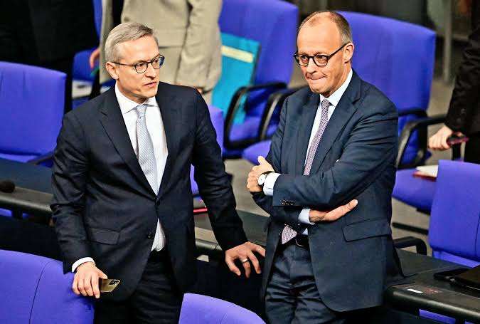 Karsten Wildberger standing next to Chancellor Friedrich Merz in the Bundestag